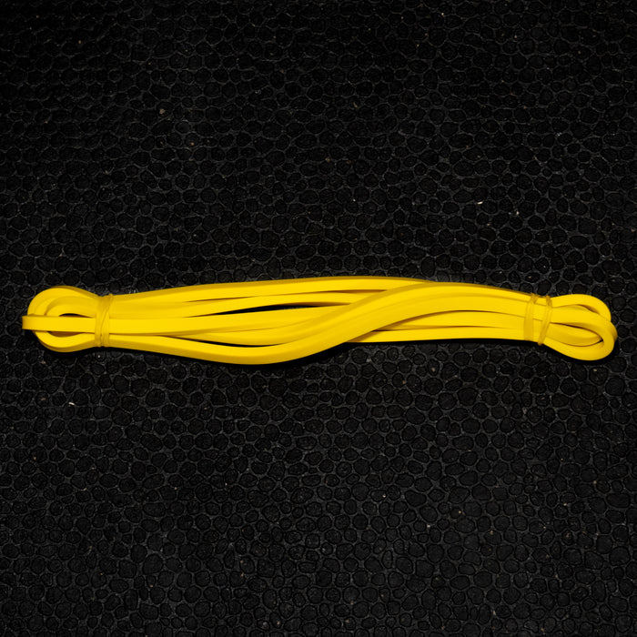 Yellow natural latex resistance band coiled on a black mat