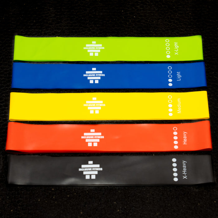 Fabric mini loop hip bands in green, blue, yellow, orange and black, labelled by resistance from extra light to extra heavy