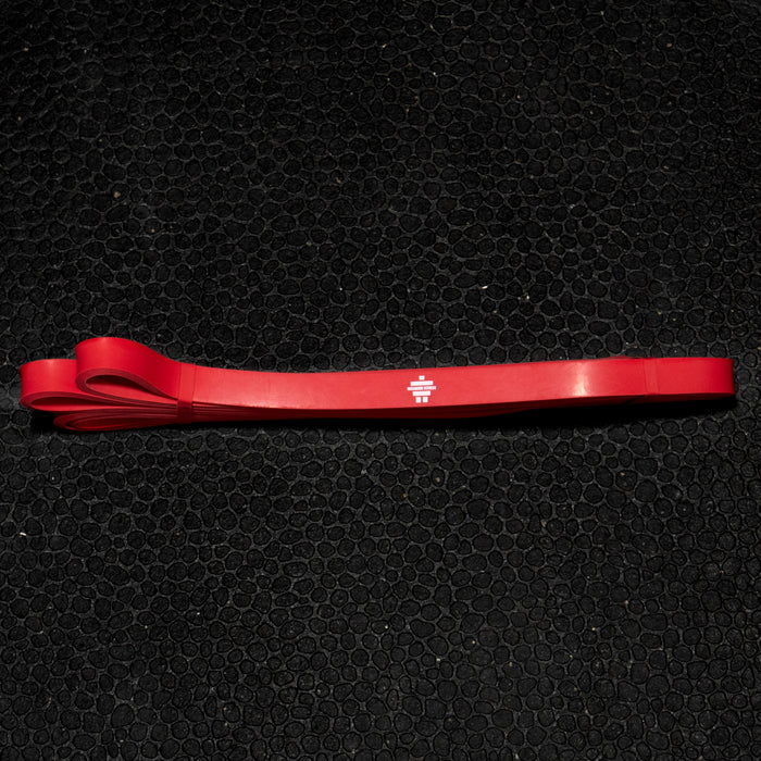 Red natural latex resistance band laid flat on a black mat